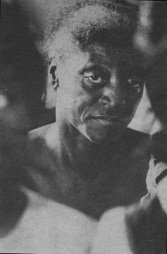 older woman seen between heads of people seated in front of her