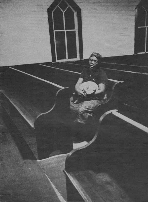 woman with bundle on lap sitting on pew in otherwise empty church